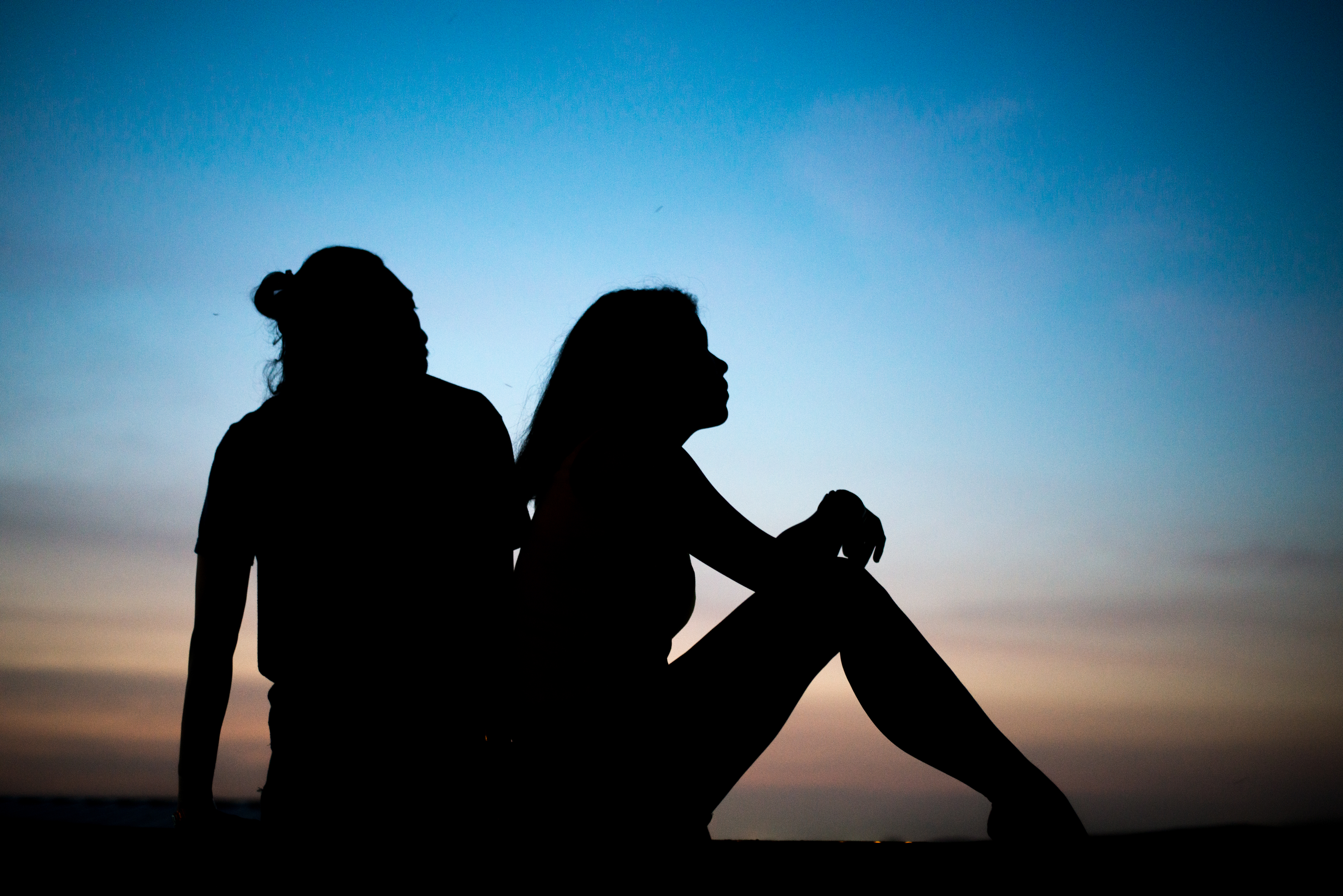 couple sitting back to back in silhouette